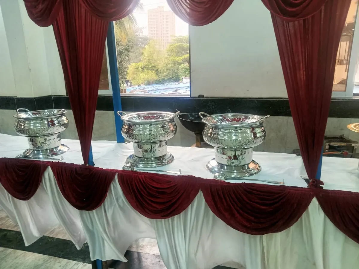 Silver handis on a buffet table with a maroon drape