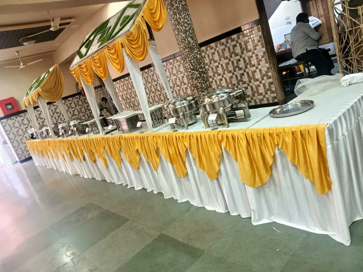 Buffet table with yellow drape and silver chafing dishes